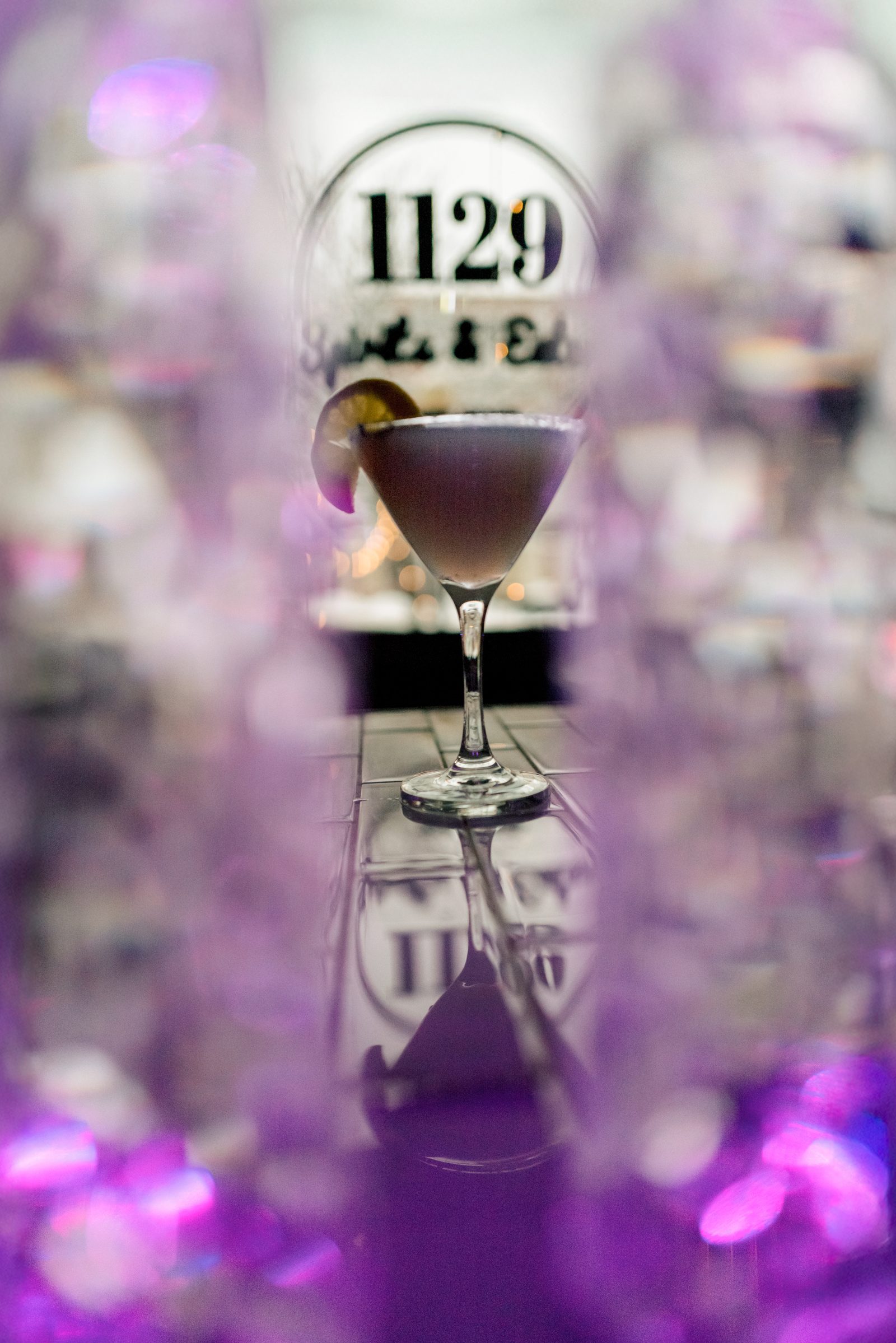 Purple cocktail photographed with the 1129 window logo behind it