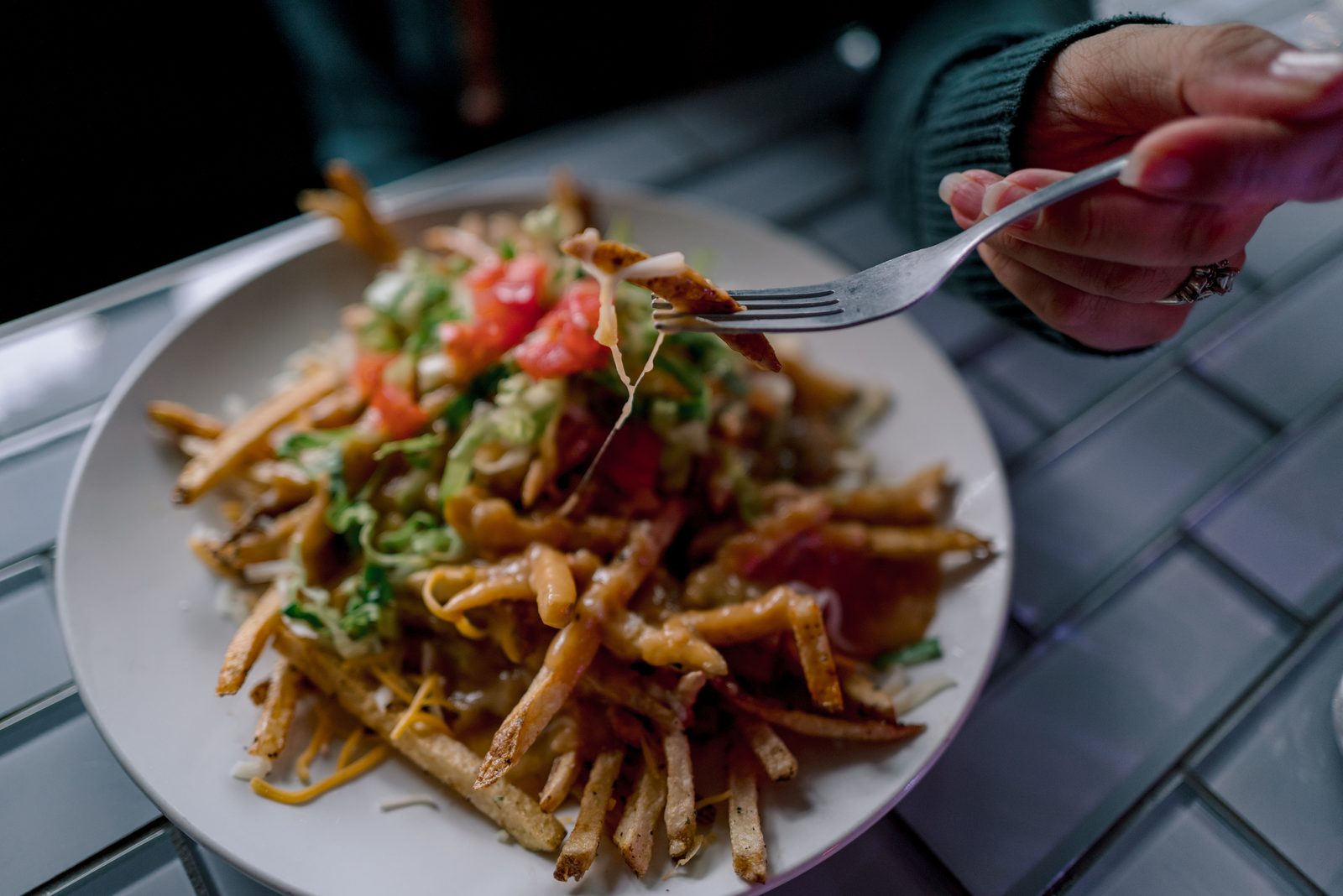 Loaded fries with a guest lifting a bite at 1129