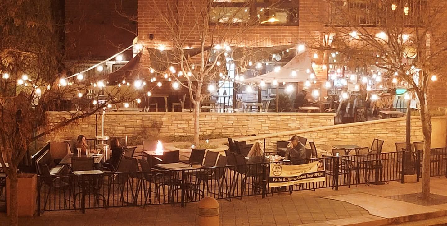 The 1129 Riverwalk patio glowing under string lights at night